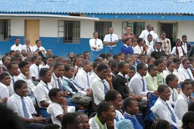 Students from the local school listen to the singing